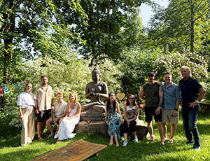 Vorschau Betriebsausflug: Mitarbeitende im Garten der Metta Vihara um lebensgroße Buddhastatue