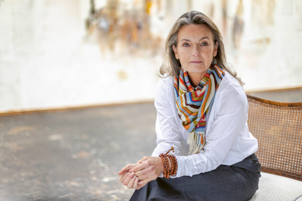 Beate Aldag auf einem Stuhl vor hellem Hintergrund